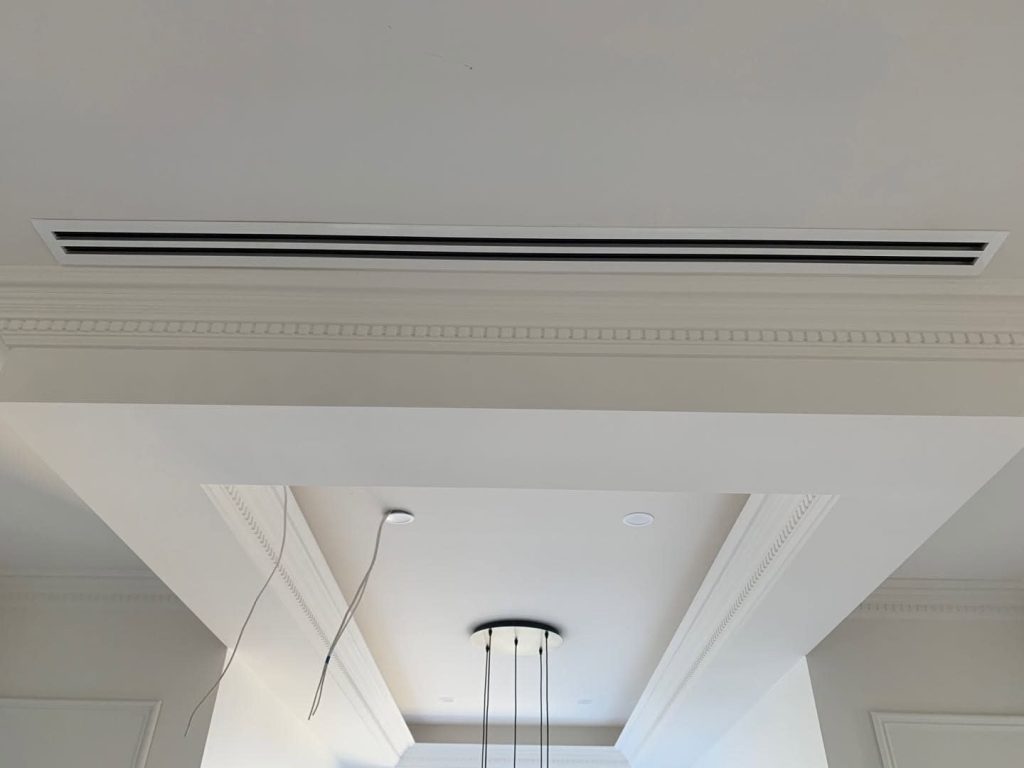 Concealed ducted air conditioning with a slot diffuser set flush beside ornate dentil cornice in a heritage Melbourne home